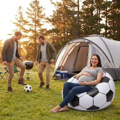 En camping, femme enceinte assise sur un canapé gonflable match foot, regardant 2 hommes dribbler un ballon.
