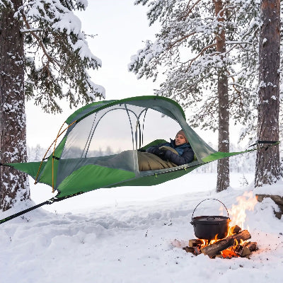 En hiver, dans la neige un homme dans son hamac tente 4 saisons suspendu