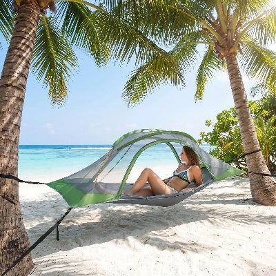 Sur la plage une jeune femme prend du soleil dans son hamac tente 4 saisons suspendu.