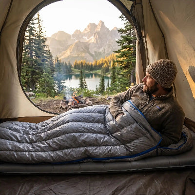 homme reveille dans sac de couchage 3 saisons devant paysage montagnard