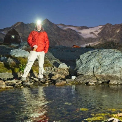Homme voit l'eau devant, grâce à sa Lampe frontale rechargeable 