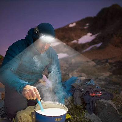 Il prépare son repas portant sa lampe frontale puissante étanche.