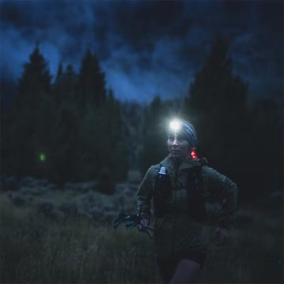 Femme en randonnée avec lampe frontale puissante