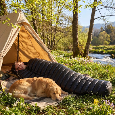 printemps pres lac il dort dans sac de couchage duvet d'oie ultraleger avec chien