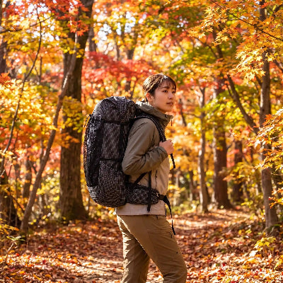 Jeune femme portant son sac à dos de randonnée Qidian Pro 56 L en sentier automnal en forêt
