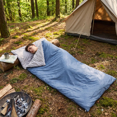 il dort dans son sac de couchage impermeable dans un boise