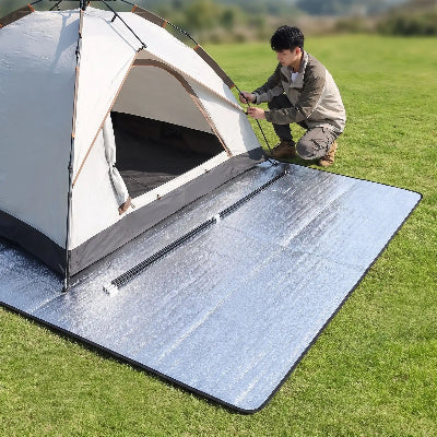 Il installe une tente sur tapis de sol camping imperméable.