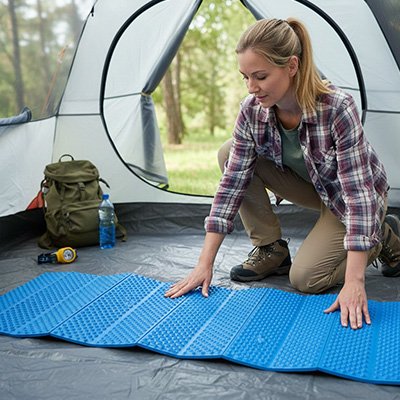 Elle étend son tapis de sol camping ultra-résistant dans sa tente