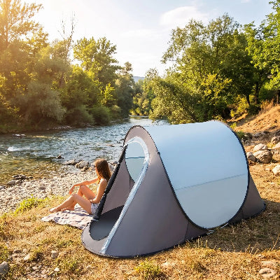 En été, femme admire rivière près de tente camping popup express