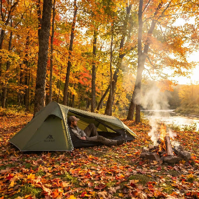 Un homme relaxe sous sa tente de camping tunnel, en automne.